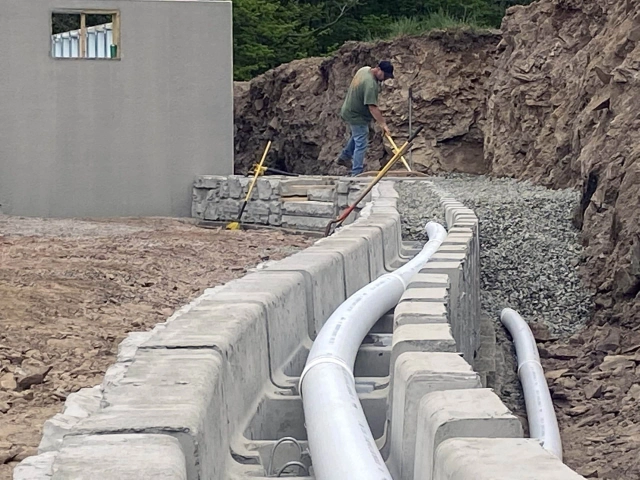 Retaining wall drainage system installation job site in Cincinnati with excavation and construction crew