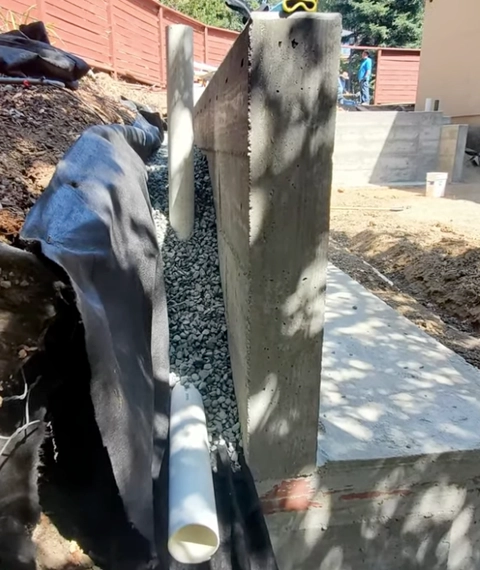 Retaining wall drainage system installation with gravel backfill and perforated pipe in Cincinnati
